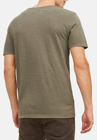 Olijf groene T-shirt met korte mouwen, een ronde halslijn en een eenvoudige uitstraling. Zachte textuur met een licht aansluitende pasvorm, geen zichtbare patronen of versieringen.
