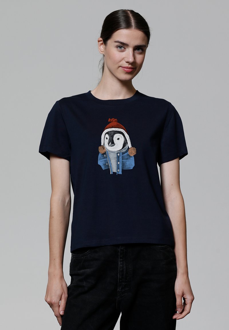 Navyblauwe katoenen t-shirt met een geborduurde pinguïn in een rode hoed en spijkerjack, met bruine pompons op de capuchon van de jas.