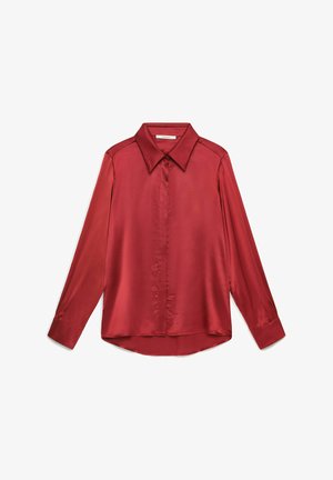 Blouse rouge en satin à manches longues avec col pointu et boutons cachés sur le devant, posée à plat sur un fond blanc.