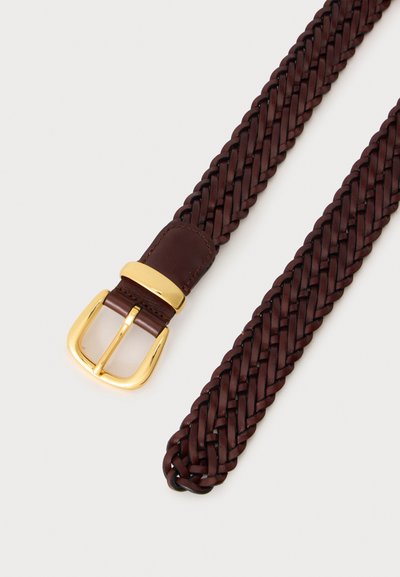 Ceinture en cuir brun foncé tressée avec une boucle métallique dorée brillante sur un fond clair.