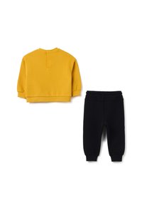 Geel cropped sweatshirt met een ronde halslijn en elastische manchetten, gecombineerd met zwarte joggerbroeken met elastische taille en taps toelopende benen.
