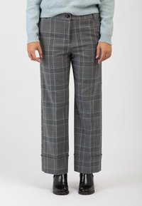 Pantaloni larghi a quadri grigi con un motivo a quadri blu, caratterizzati da una vestibilità rilassata, tasche laterali e orli arrotolati, abbinati a stivaletti neri alla caviglia.
