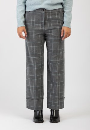 Pantaloni larghi a quadri grigi con un motivo a quadri blu, caratterizzati da una vestibilità rilassata, tasche laterali e orli arrotolati, abbinati a stivaletti neri alla caviglia.