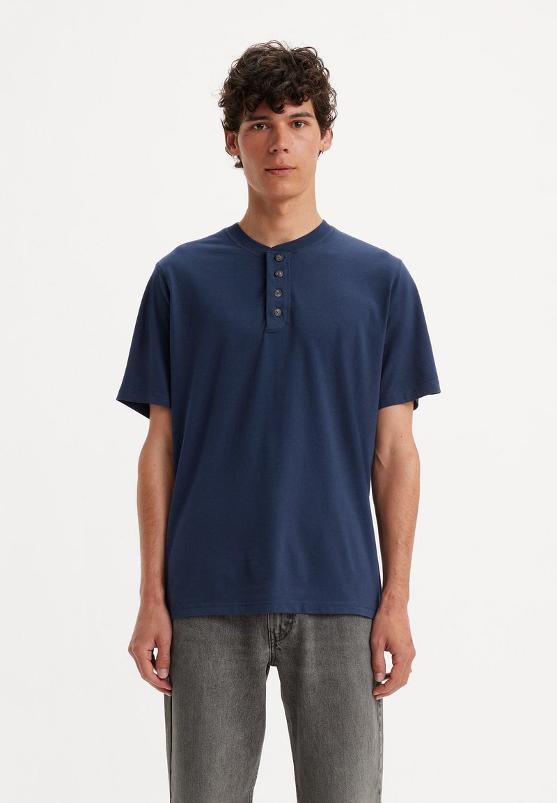 Maglietta henley a maniche corte di colore blu navy, realizzata in tessuto morbido, con apertura a tre bottoni, vestibilità comoda e design minimalista.