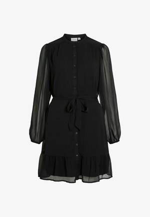Abito nero con bottone anteriore, maniche lunghe trasparenti, orlo arricciato e cintura legata in vita. Realizzato in tessuto leggero.