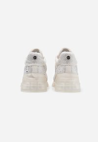 Baskets blanches avec tige en mesh ornée de strass argentés, semelles translucides et design distinct sans lacets.