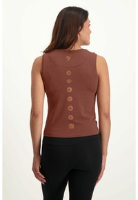 Ruskea ilmanhiha toppi, jossa on muotoiltu malli, jossa on kultaiset brodeeratut chakrasymbolit pystysuoraan selkäpuolella ja hienovarainen kaula-aukko.