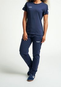 Conjunto deportivo de color azul marino que incluye una camiseta de manga corta y pantalones, fabricado en tejido suave, con un logo en el pecho y en la pierna.