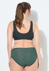 Tmavě zelený, bezramínkový bikiny top s nízkým zadním dílem, spárovaný s vysokými pruhovanými bikinami v tmavě zelené a světle zelené barvě.