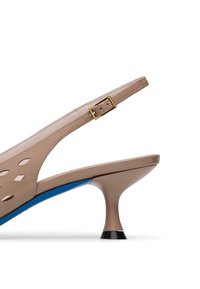 Tacco slingback beige con design intagliati, soletta blu, tacco curvato e dettaglio della fibbia dorata. Texture della pelle liscia.