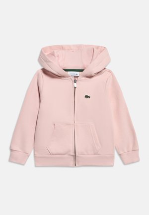 Ανοιχτό ροζ hoodie με φερμουάρ πλήρους μήκους, εμπρόσθιες τσέπες, ριμπ μανσέτες και τελείωμα, κουκούλα και μικρό πράσινο λογότυπο κροκόδειλου Lacoste στο αριστερό στήθος.