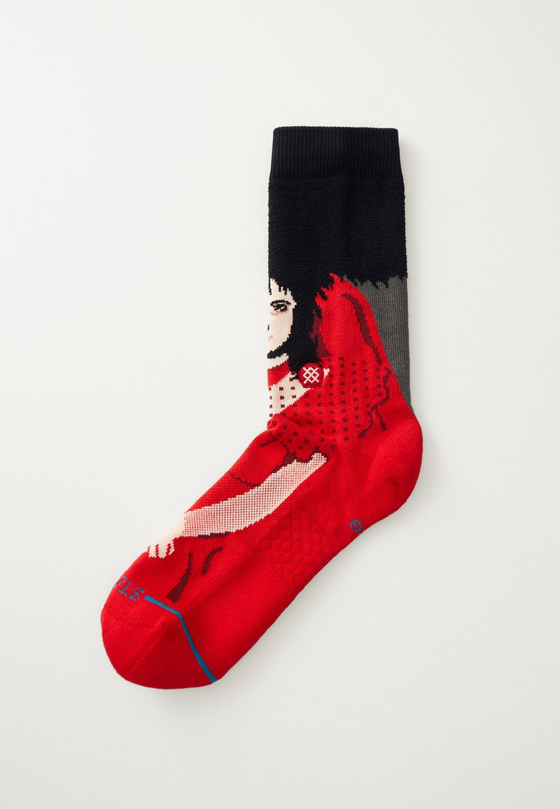 Calcetín con un diseño gráfico en rojo, negro y gris que representa una figura estilizada. Textura de punto con patrones de puntos y puño acanalado.