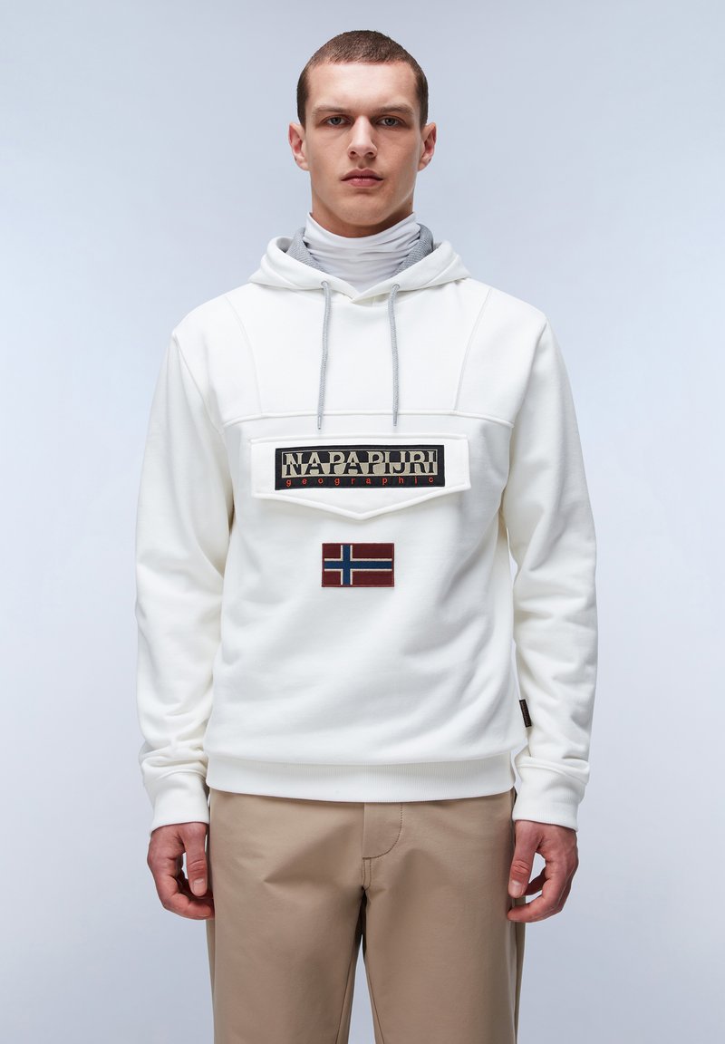Sudadera blanca con capucha y un gran parche negro que muestra el texto "NAPAPIJRI geographic" y un emblema de la bandera de Noruega en rojo y azul en la parte delantera.