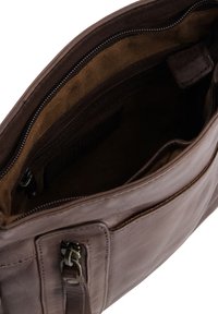 Brązowa skórzana torba na ramię o gładkiej teksturze, z zamykanym głównym kompartamentem oraz dodatkową zamykaną kieszenią. Wnętrze wykonane jest z beżowej tkaniny.