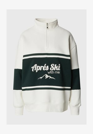 Bílá a tmavozelená mikina s krátkým zipem vyrobená z měkkého materiálu, s výšivkou "Aprés Ski with me" a horským motivem, doplněná o pruhované detaily.