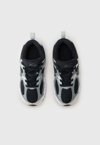 Des baskets noires et argentées avec une tige en mesh respirant, des accents texturés, un col rembourré et une semelle en caoutchouc avec une languette.