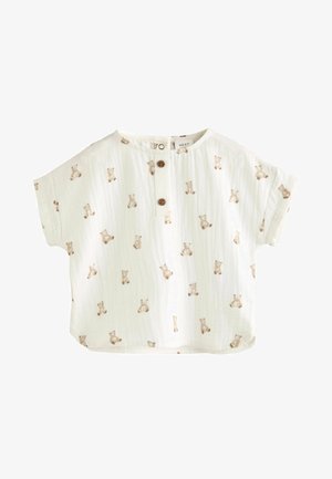 Fehér, rövid ujjú felső, gombos záródással, világosbarna, ismétlődő medve mintával, puha, struktúrált anyagból készült.