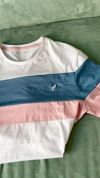 Striped short-sleeve t-shirt featuring horizontal bands in white, light pink, and blue with a small bird logo in white on the chest.