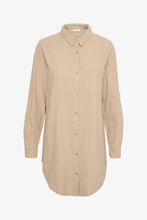 Chemise beige à manches longues avec un devant à boutons, un col, une poche poitrine unique et un ourlet arrondi. Fabriquée dans un tissu doux et texturé.