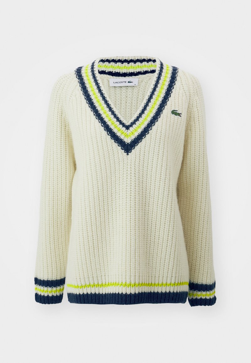 Pull en tricot crème avec un col en V, arborant des rayures bleu marine, vert lime et blanc. Comprend un petit logo Lacoste sur la poitrine.