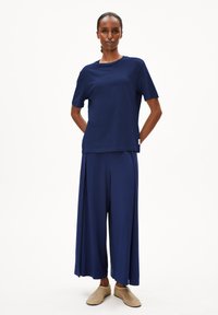 Navyblauwe katoenen t-shirt en wijde broek met een relaxte pasvorm, met een rechte zoom en een zachte textuur. Gedragen met lichte schoenen.