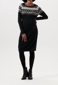 Svart stickad klänning med långa ärmar, med en mönstrad ok i vitt och grått. Accentuerad med gråmanschetter och klassiska ankelstövlar.