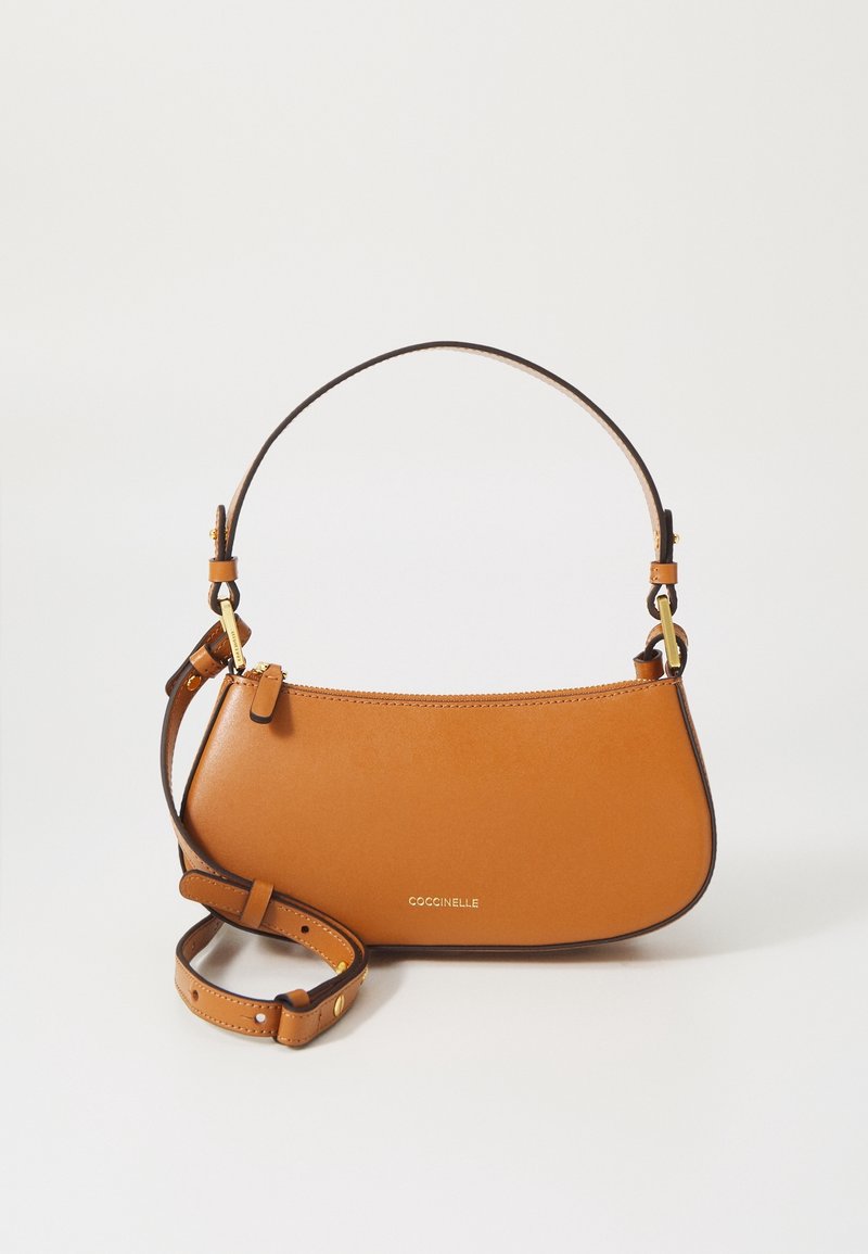 Sac à main en cuir cognac avec ferrures dorées, bandoulière réglable et logo "Coccinelle" sur le devant.