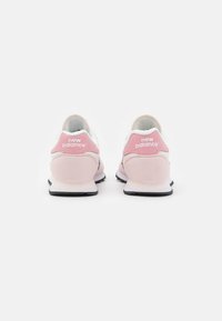Paire de baskets New Balance rose clair vues de dos sur fond blanc, mettant en avant le logo de la marque sur les languettes des talons.