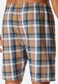 Shorts à carreaux pour hommes en marron, bleu et violet. Fabriqués en tissu léger avec une taille élastique et des poches latérales.