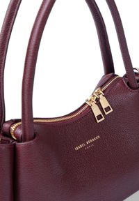 Sac à main en cuir bordeaux avec deux anses courtes, accents de fermeture éclair dorés et finition texturée. Présente le nom de la marque sur le devant.