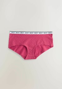 Red polka-dot cotton boyshorts with a black and white elastic waistband labeled "NEXT." Smooth texture, casual design.