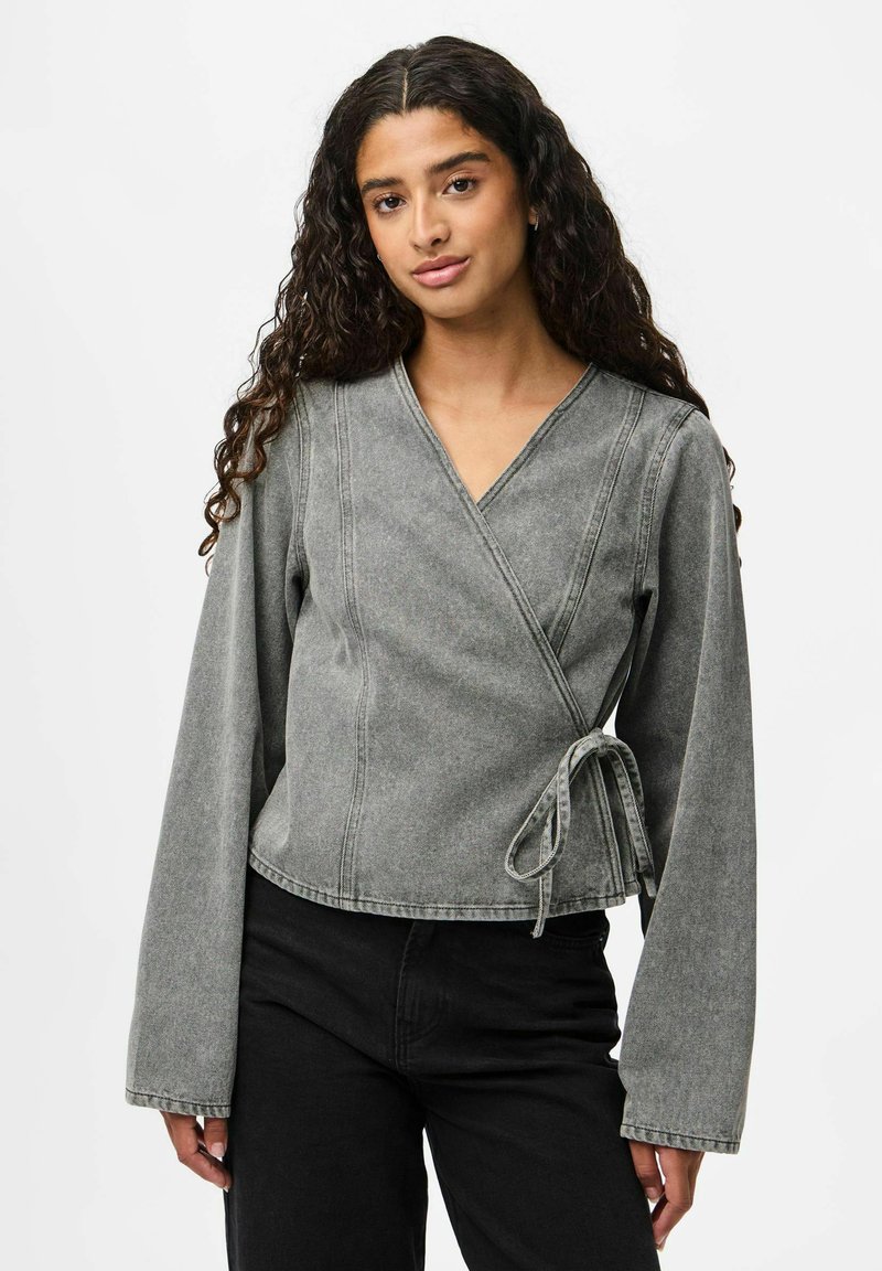 Top envolvente de denim gris con un escote en V profundo, mangas largas y detalle de lazo en la cintura; presenta costuras limpias y un diseño corto.