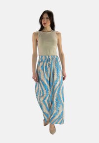 Beige tajt linne parat med en flödande mönstrad maxikjol i blåa och persikofärgade nyanser med ett zigzag-mönster, elastisk midja.