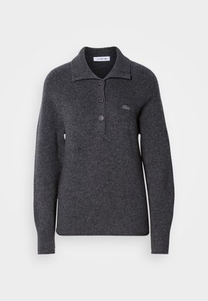 Pulover din lână gri închis, cu guler, trei nasturi în față, mâneci lungi și mansete cu dantelă. Logo-ul Lacoste pe partea stângă.