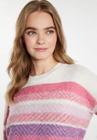 Krém színű kötött pulóver, vízszintes pink, lila és lila csíkokkal. Texturált mintával és kerek nyakkivágással rendelkezik. Puha anyag.