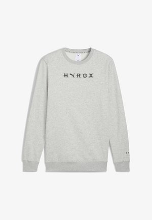Sweatshirt gris en tissu doux, avec un col rond, des longues manches et un logo "HYROX" brodé en noir sur la poitrine.