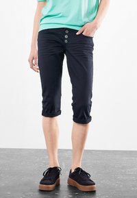 Granatowe krótkie spodnie z podwiniętymi mankietami, z zapięciem na guziki i trzema guzikami z przodu, zestawione z czarnymi trampkami i miętowym topem.