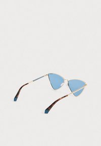 Svetle zlato obrobljena mačja očala s plavimi lečami in školjkastimi nasloni za ušesa, ki ležijo na beli površini.