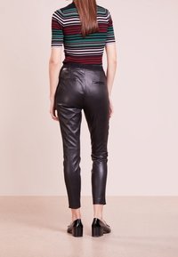 Svarta läderbyxor med slim fit, med bakfickor och en slät textur. Bärs med en randig kortärmad topp.