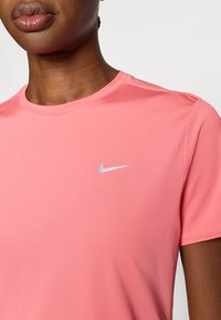 Ροζ μπλουζάκι Nike κατασκευασμένο από απαλό, ελαφρύ ύφασμα. Διαθέτει στρογγυλή λαιμόκοψη και ένα μικρό ασημί λογότυπο swoosh στο αριστερό στήθος.