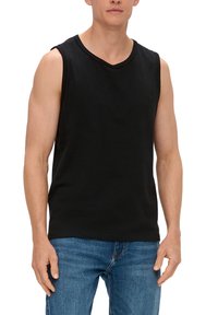 Zwarte mouwloze tanktop met een ronde hals, gemaakt van zacht materiaal; gecombineerd met lichtblauwe spijkerbroek.