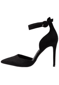 Černé semišové lodičky na kotníkovém pásku s špičatou špičkou, vysokým jehlovým podpatkem a kulatou sponou na pásku. Hladká textura.