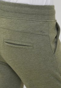 Groene, textuur sweatpants met een achterzak met klep en een klein metalen logoaccent. Zacht materiaal met een ontspannen pasvorm.