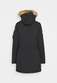 Parka noire avec capuche doublée de fourrure, fermeture éclair à l'avant et poches latérales. Comprend un patch brodé sur la manche gauche.