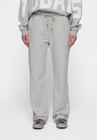 Grijze sweatpants met een elastische tailleband, een relaxte fit en een zachte textuur, gecombineerd met grijze sneakers met zilveren accenten.
