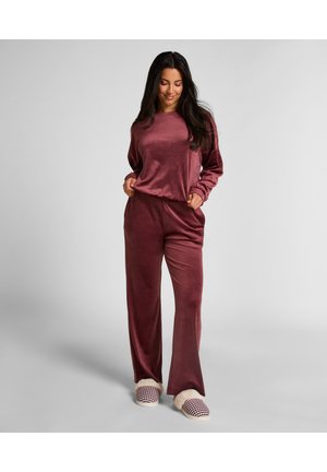 Ensemble de vêtements de maison en velours bordeaux avec des manches longues et un pantalon large. Présente une coupe décontractée et une texture douce. Accessoirisé avec des pantoufles à carreaux.