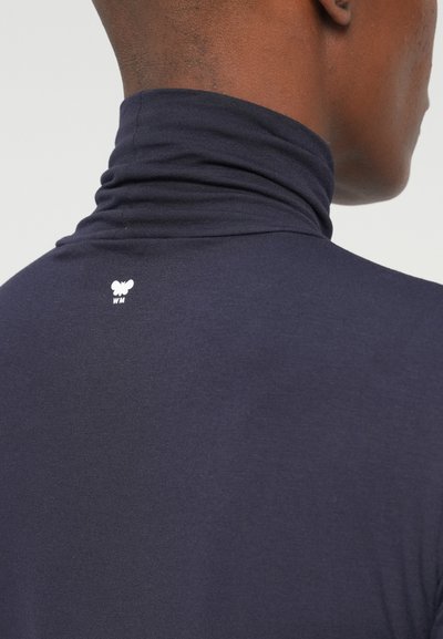 Granatowy golf wykonany z miękkiego materiału o dopasowanym kroju, z białym logo z tyłu oraz gładką, równą teksturą.