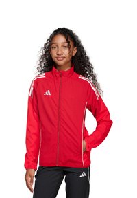 Rode sportjack met hoge kraag, ritssluitingen aan de voorkant, witte zijstrepen en het Adidas-logo. Lichtgewicht stof met elastische boorden en zoom.