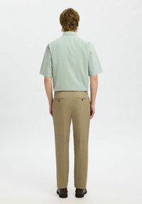 Korte mouwen, lichtgroene gestreepte shirt met een kraag, gecombineerd met beige broek met twee achterzakken en een rechte pijp.