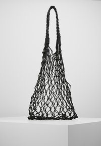 Zwarte geweven netzak met gevlochten handvat, tentoongesteld op een wit voetstuk tegen een effen achtergrond.